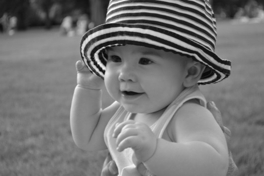 black and white photo of baby wearing striped hat and smiling