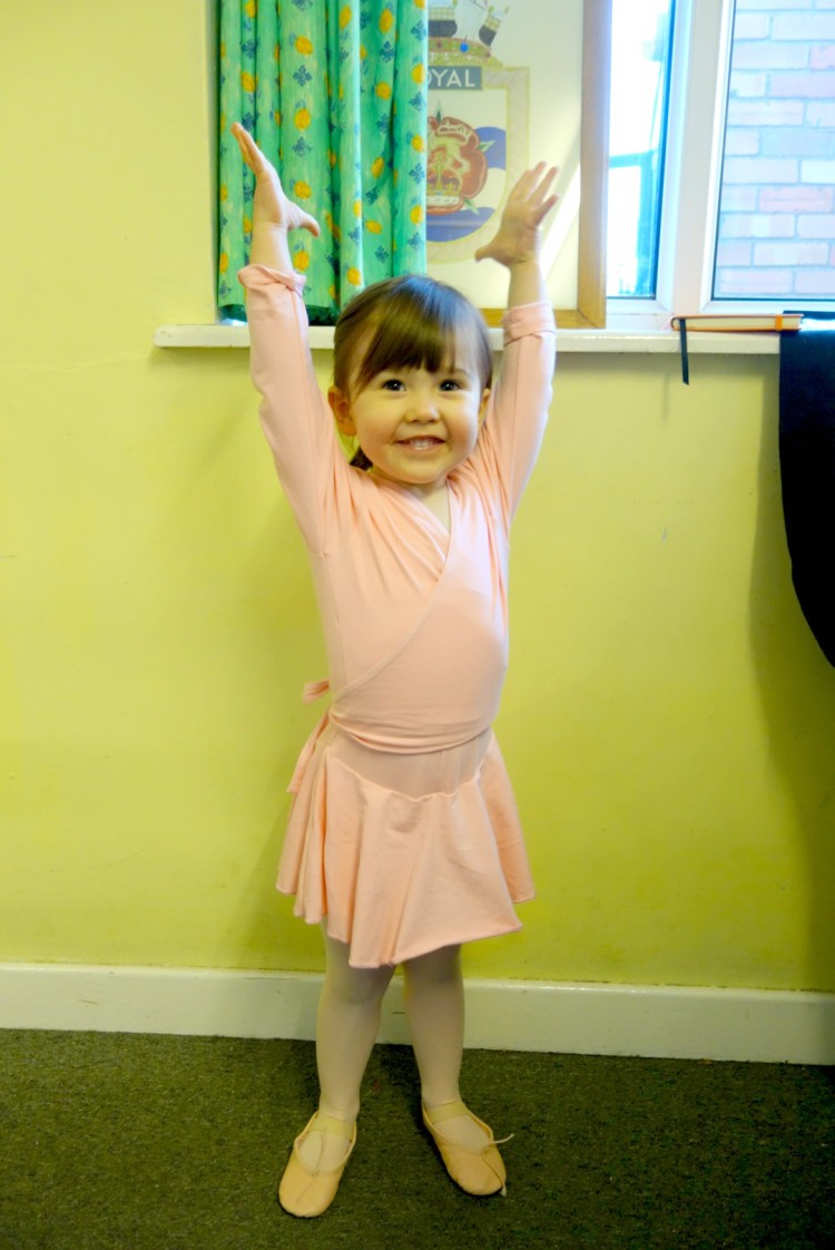 young girl in ballet outfit with arms stretched