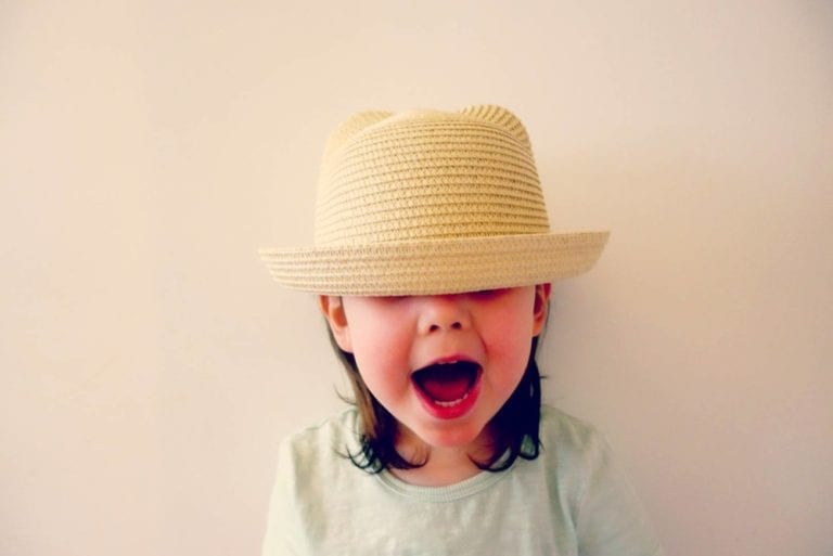 young girl smiling widely and wearing a hat