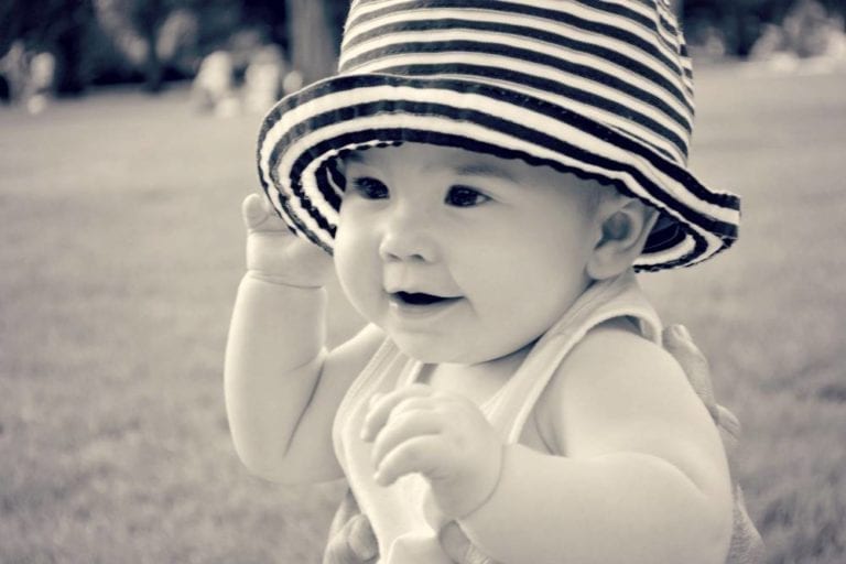 black and white photo of baby in striped hat smiling