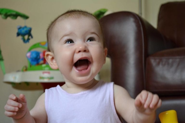 baby in pink vest smiling happily