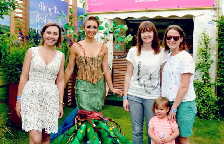 four women and a child stood facing the camera, surrounded by a set-up garden