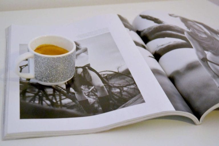 silver and white espresso cup on magazine on table