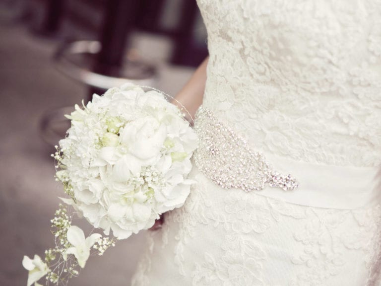 bride in wedding dress up close holding bouquet