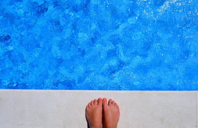 womans feet standing next a swimming pool