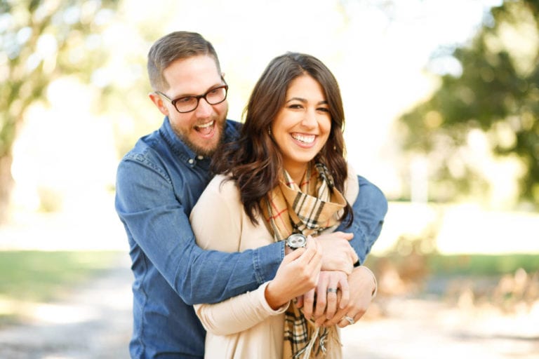 man with arms around woman and both smiling