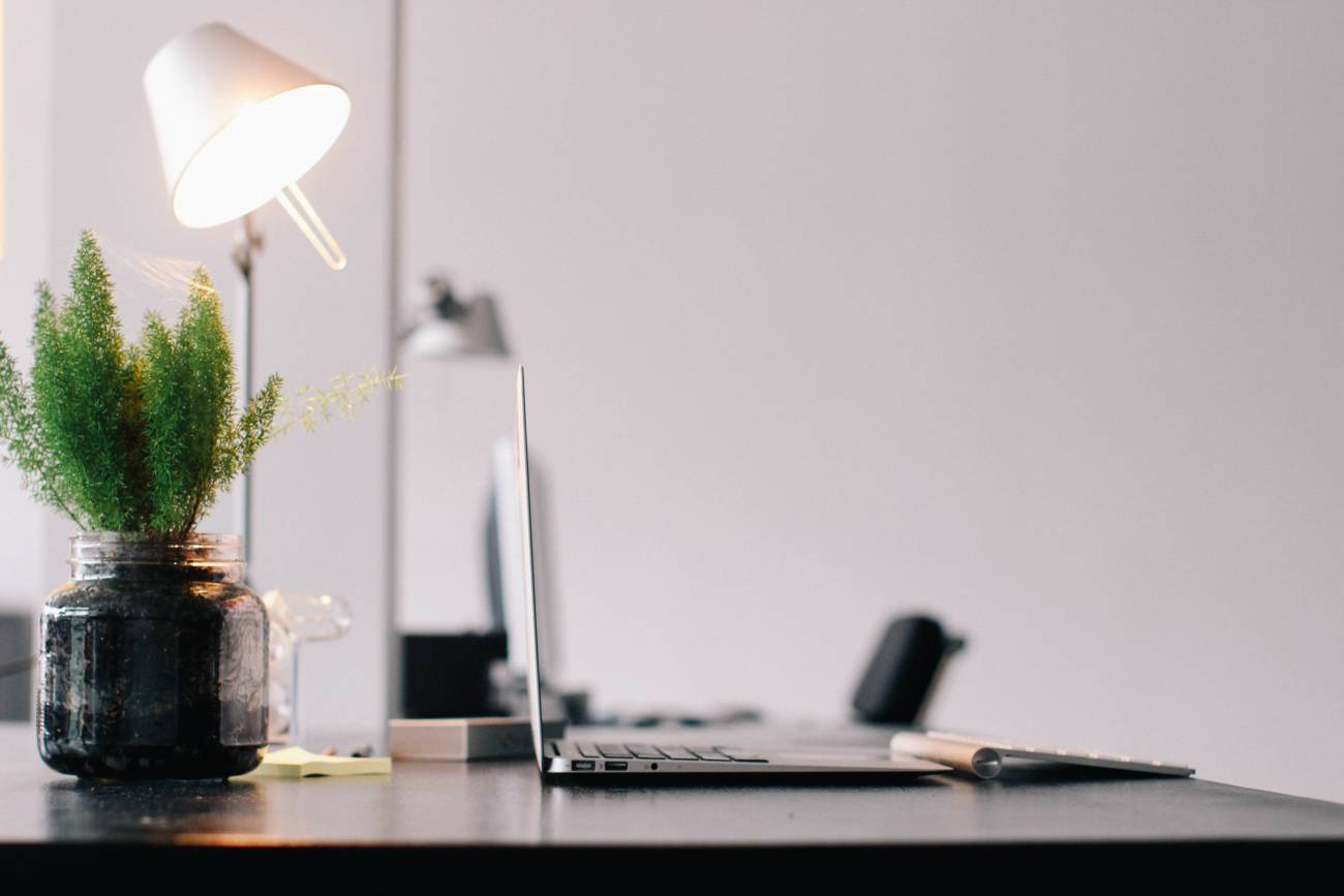Silver Laptop on Wooden Desk with lamp shining behind it