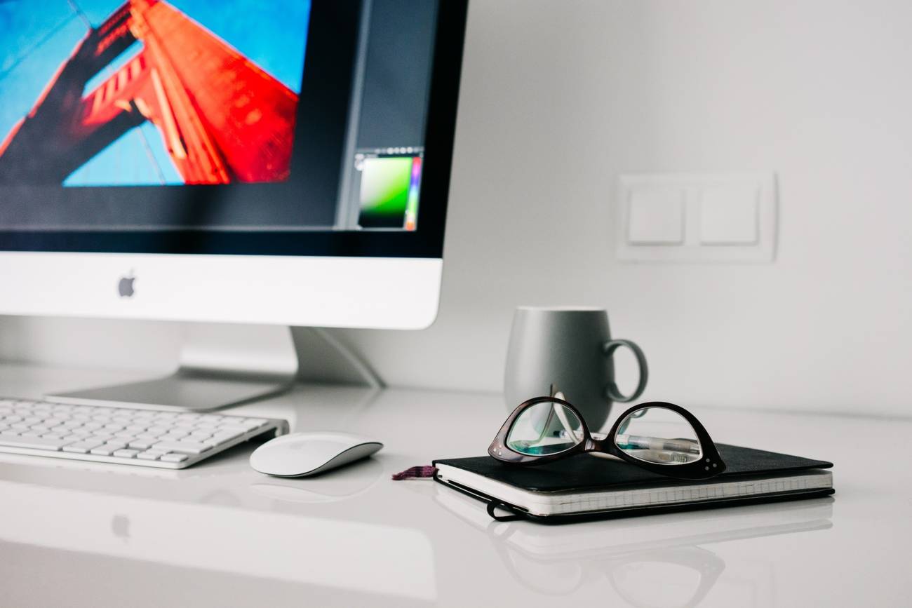 desktop computer on desk next to my and glasses