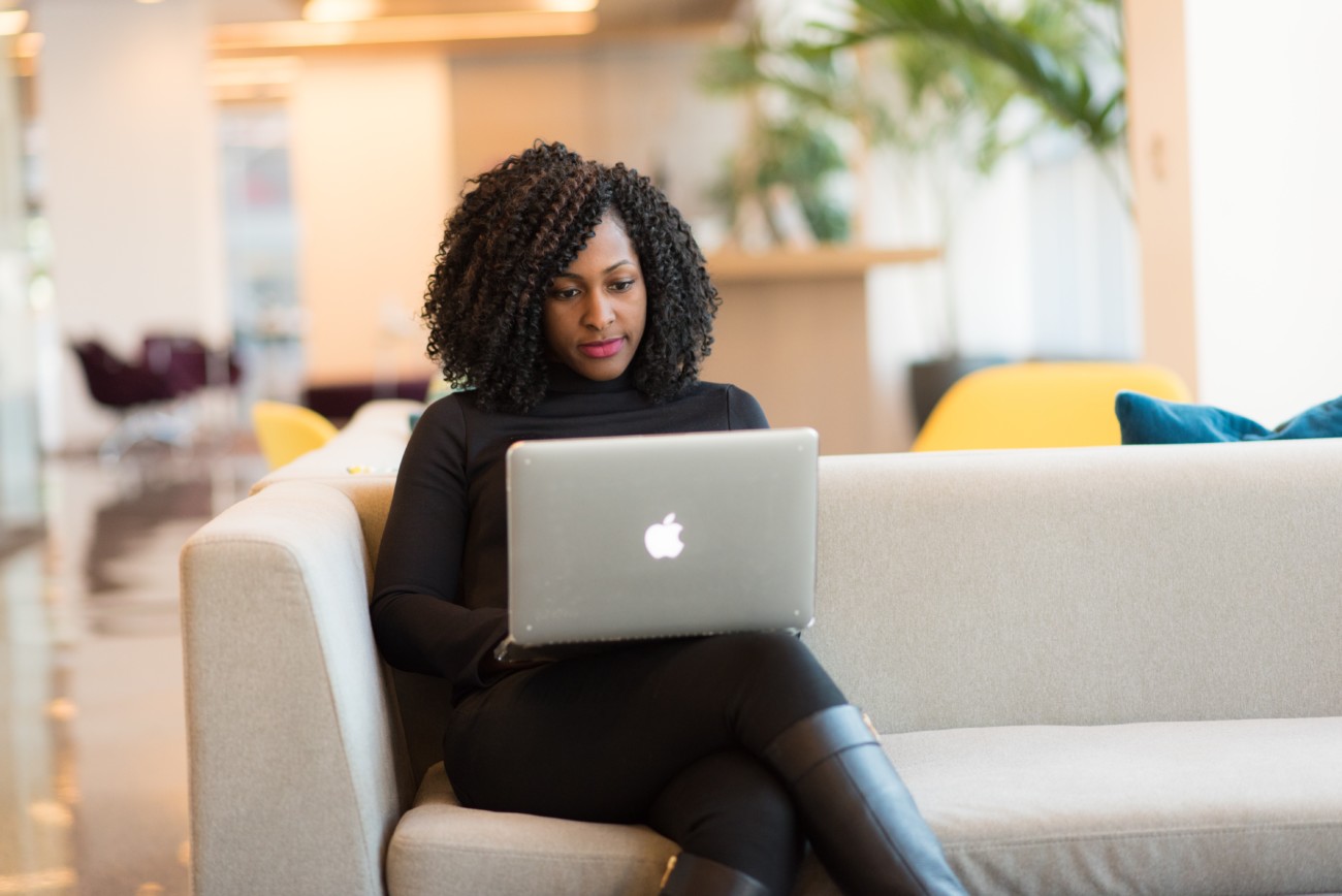 woman sitting on sofa with laptop on her knee and smiling