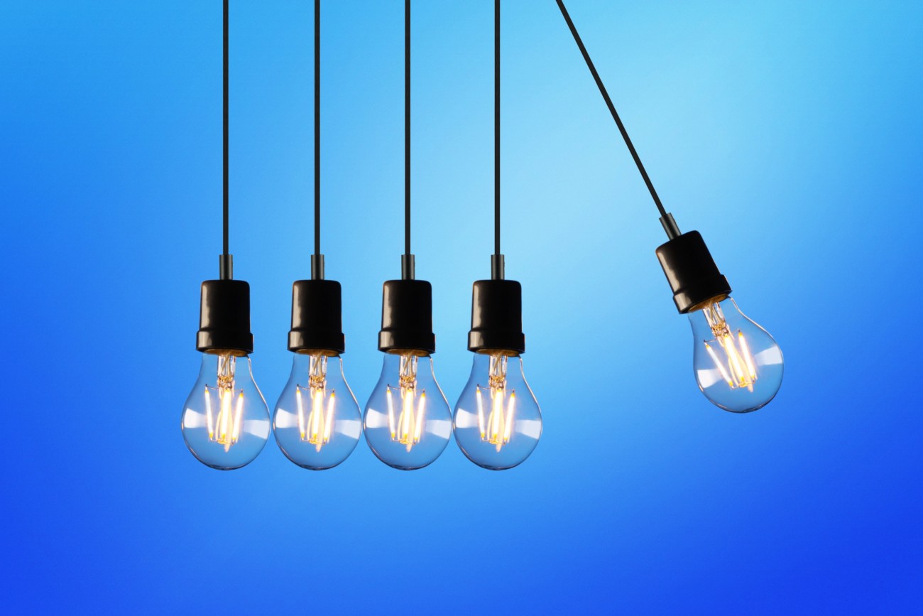 five light bulbs in sockets hanging from above with bright blue background behind