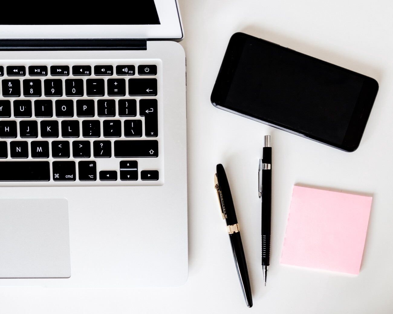 laptop, phone, pens and paper on desk