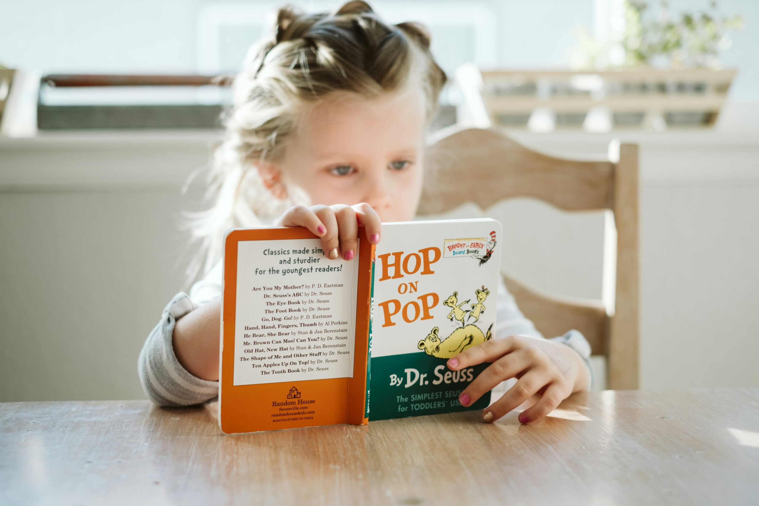 girl reading book at table at home