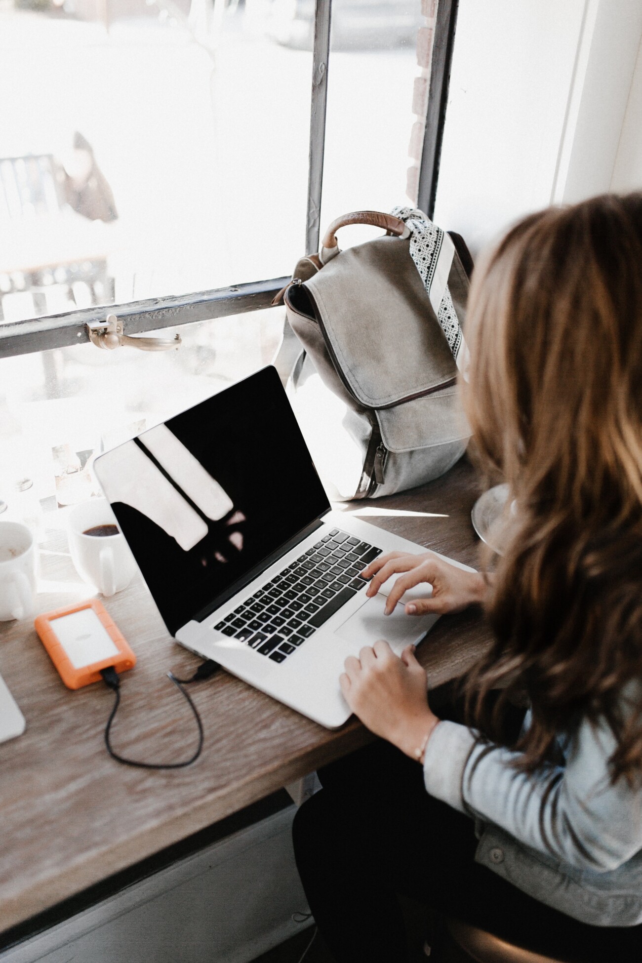 woman sitting at table in cafe on laptop