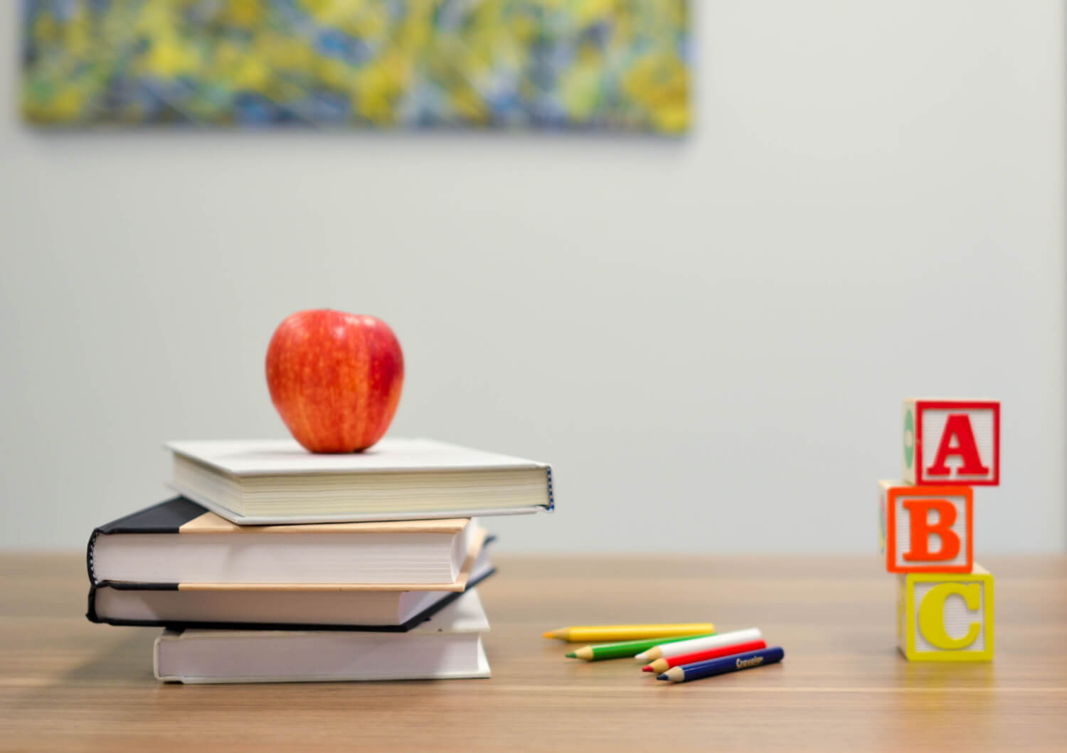 apple on top of pile of books on desk