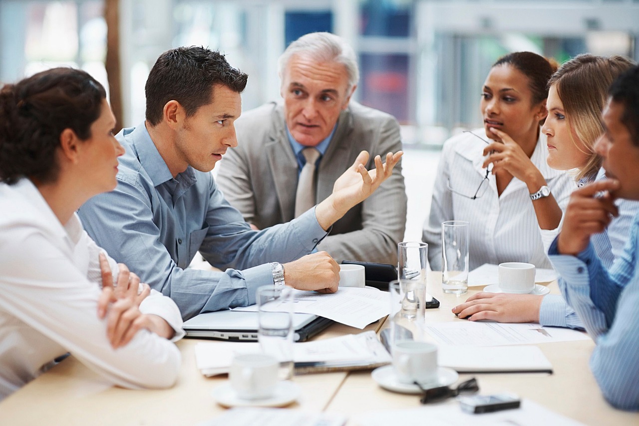 men and women sitting around a table having an expressive conversation in a business meeting