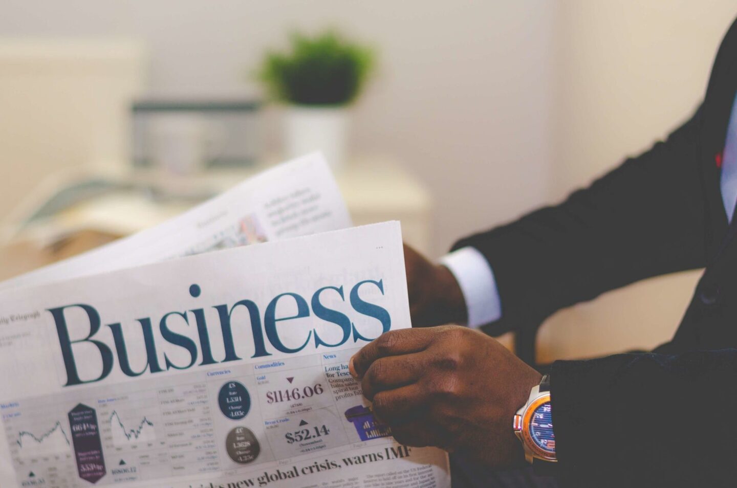 hands of man wearing suit holding business newspaper