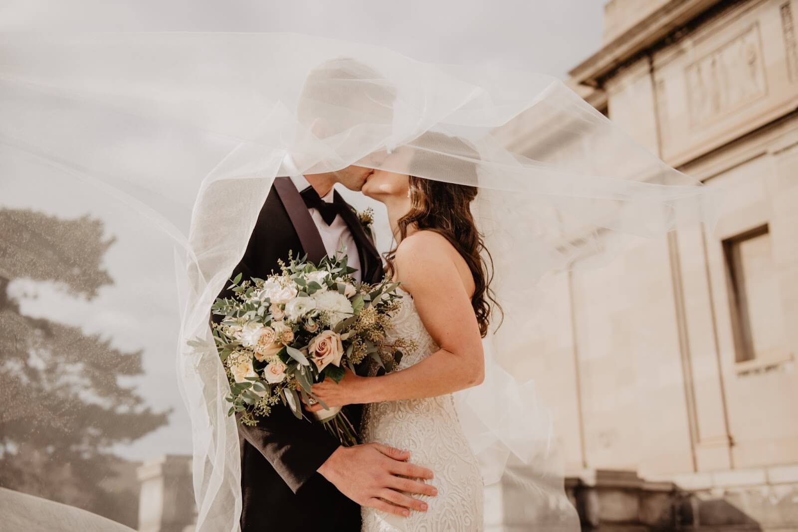 bride and groom kissing under bride's veil