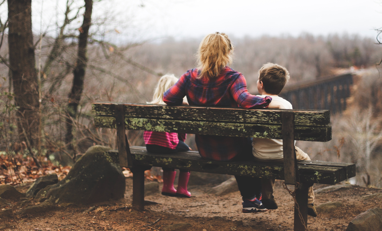 mother and two childrn sitting on bench outside