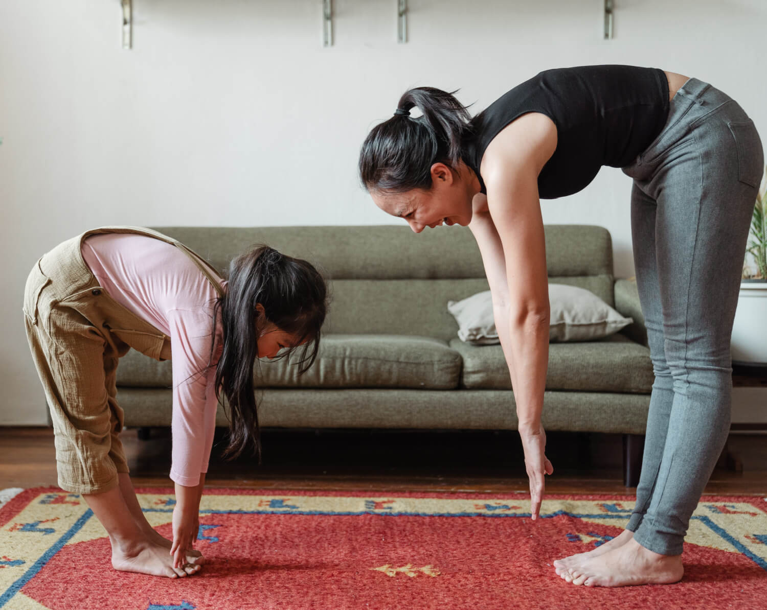 mother and young daughter stretching together in living room