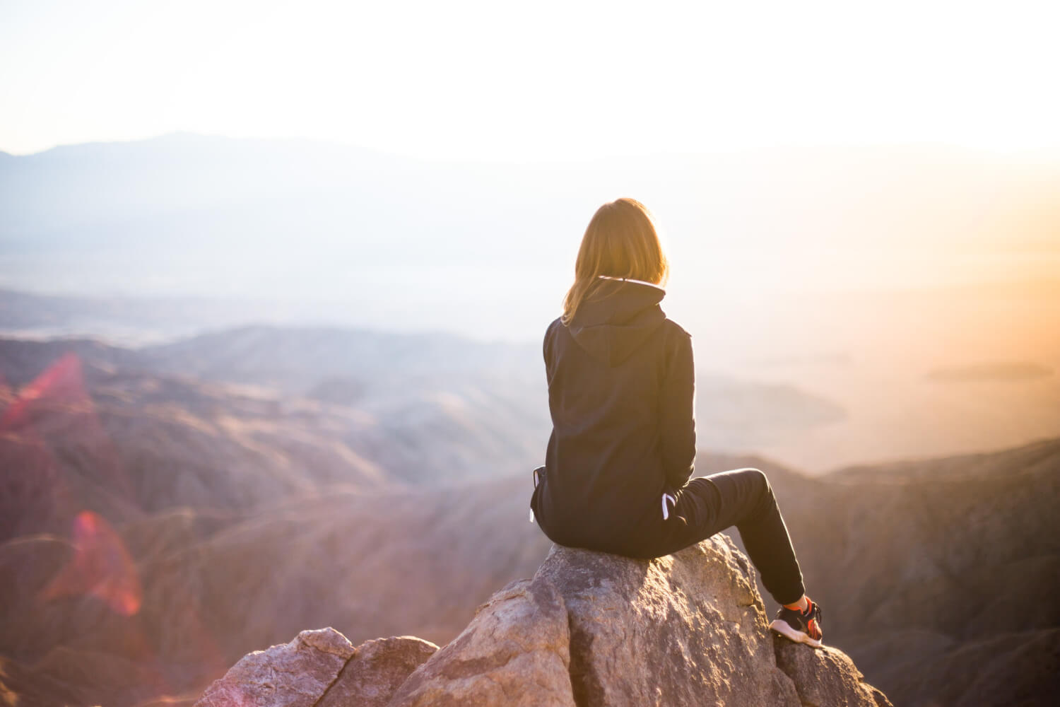 woman sitting on rock looking out at view