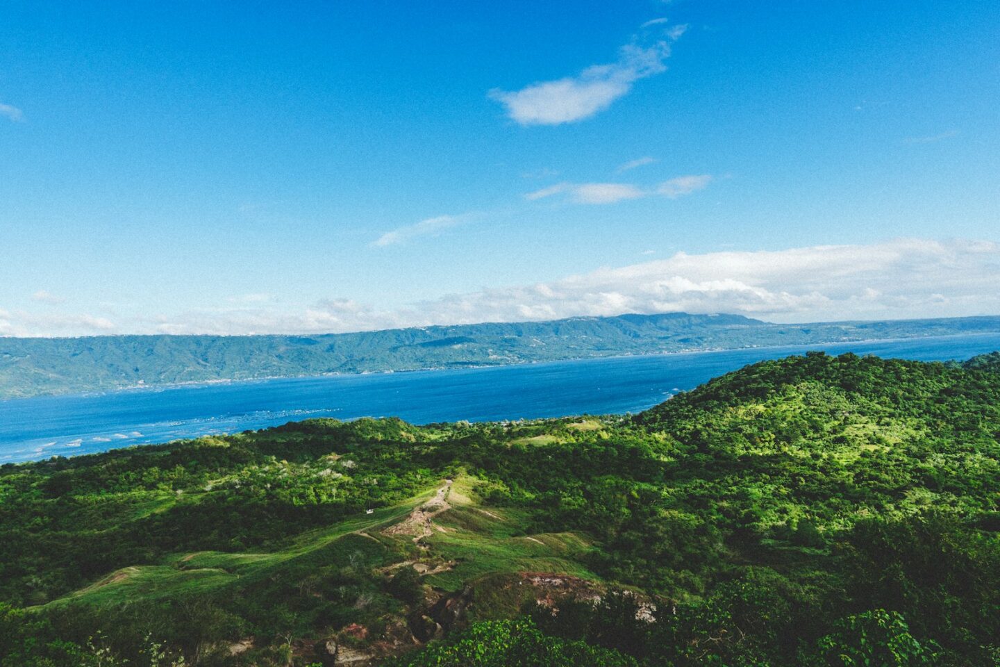 green grass field near blue sea under blue sky during daytime