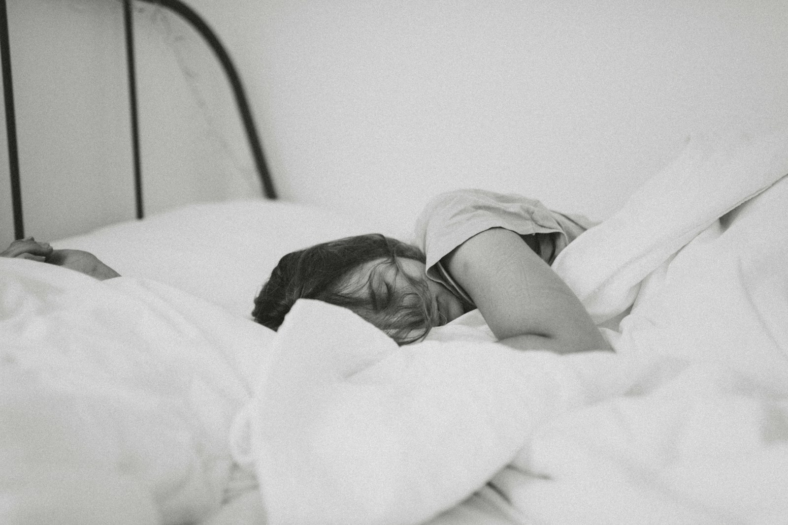 greyscale photo of sleeping woman lying on bed