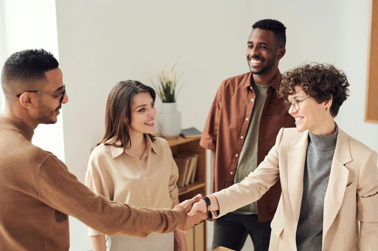 4 people smiling at each other, with 2 shaking hands