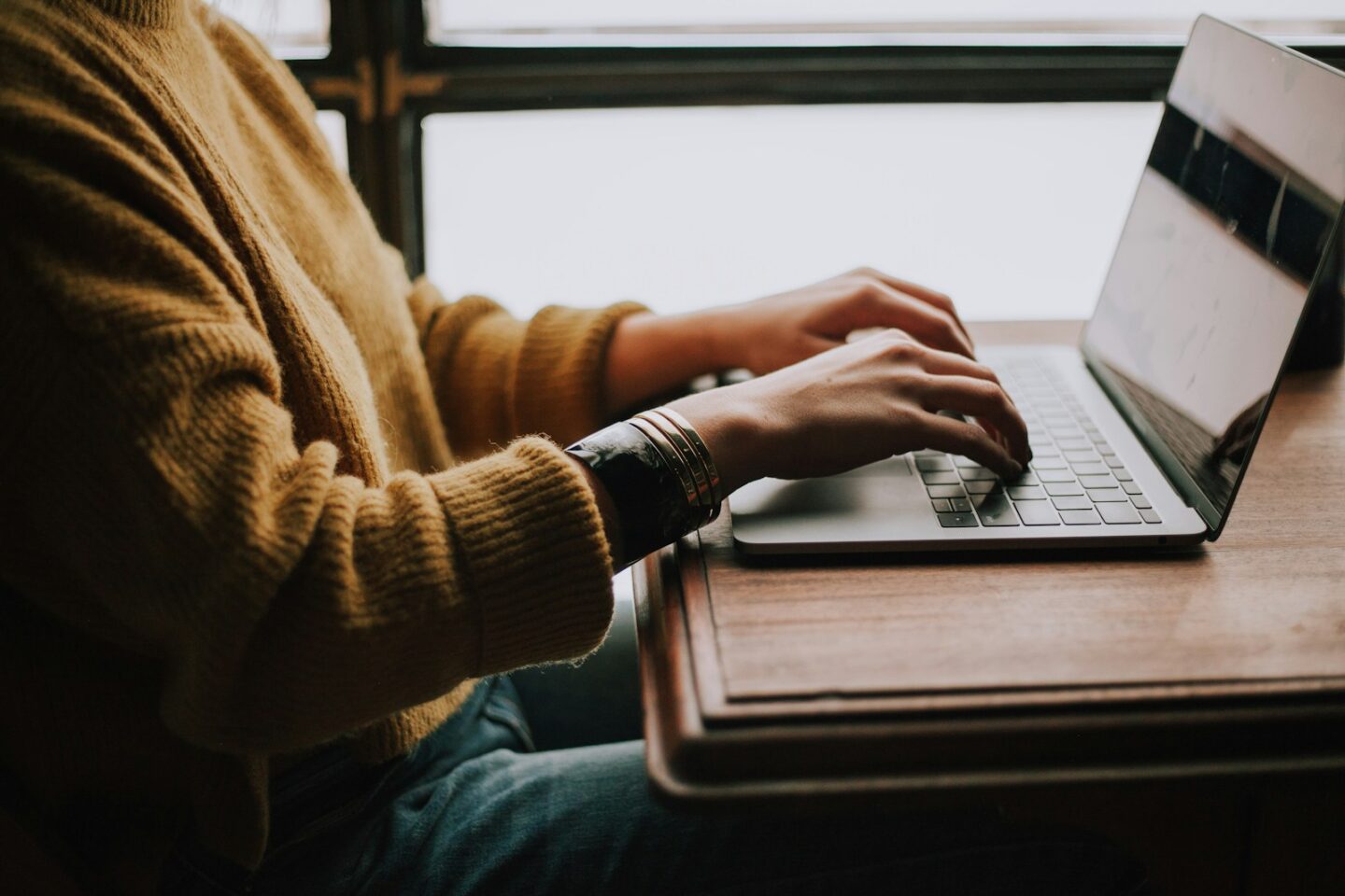person sitting front of laptop, typing
