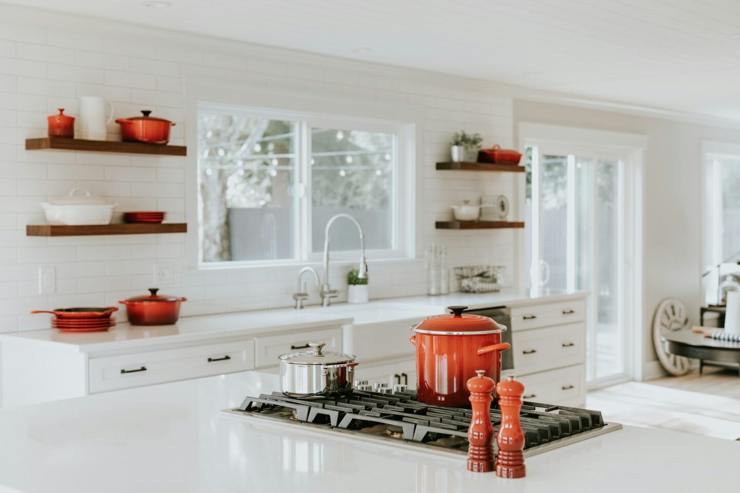 bright white kitchen with bright red cooking pots and salt and pepper mills