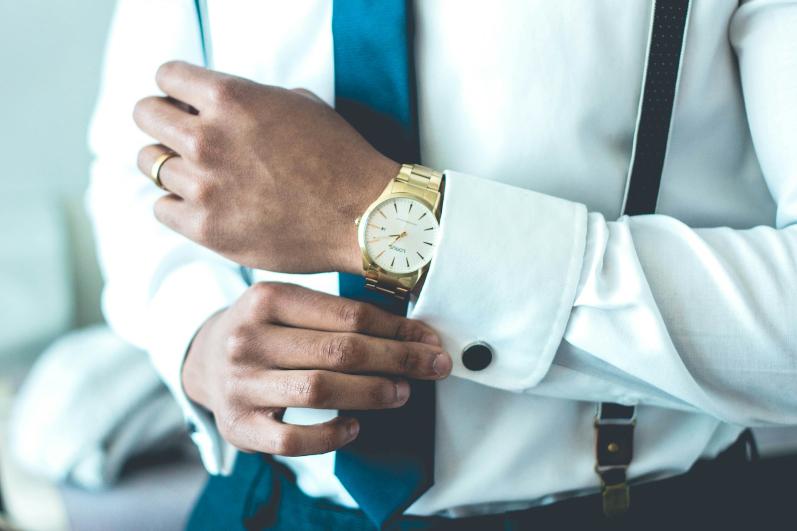 man up close wearing white dress shirt and tie and holding onto cuff