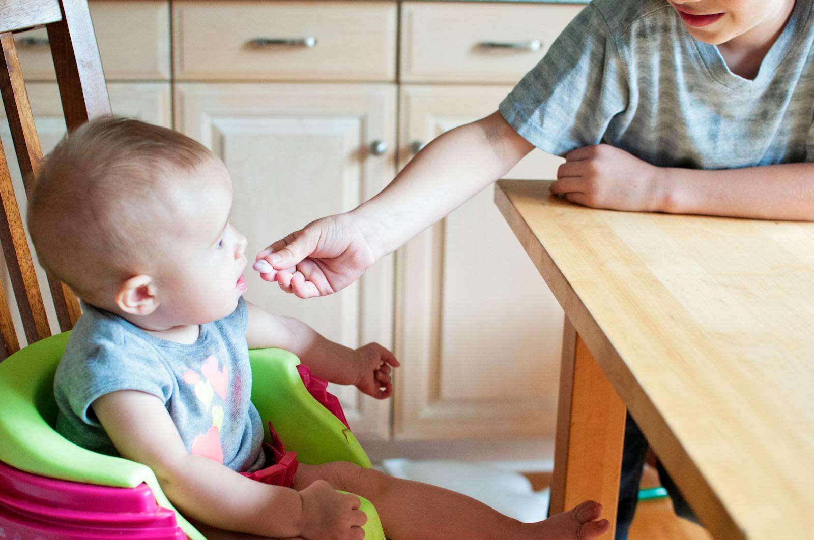 baby in highchair being fed by hand