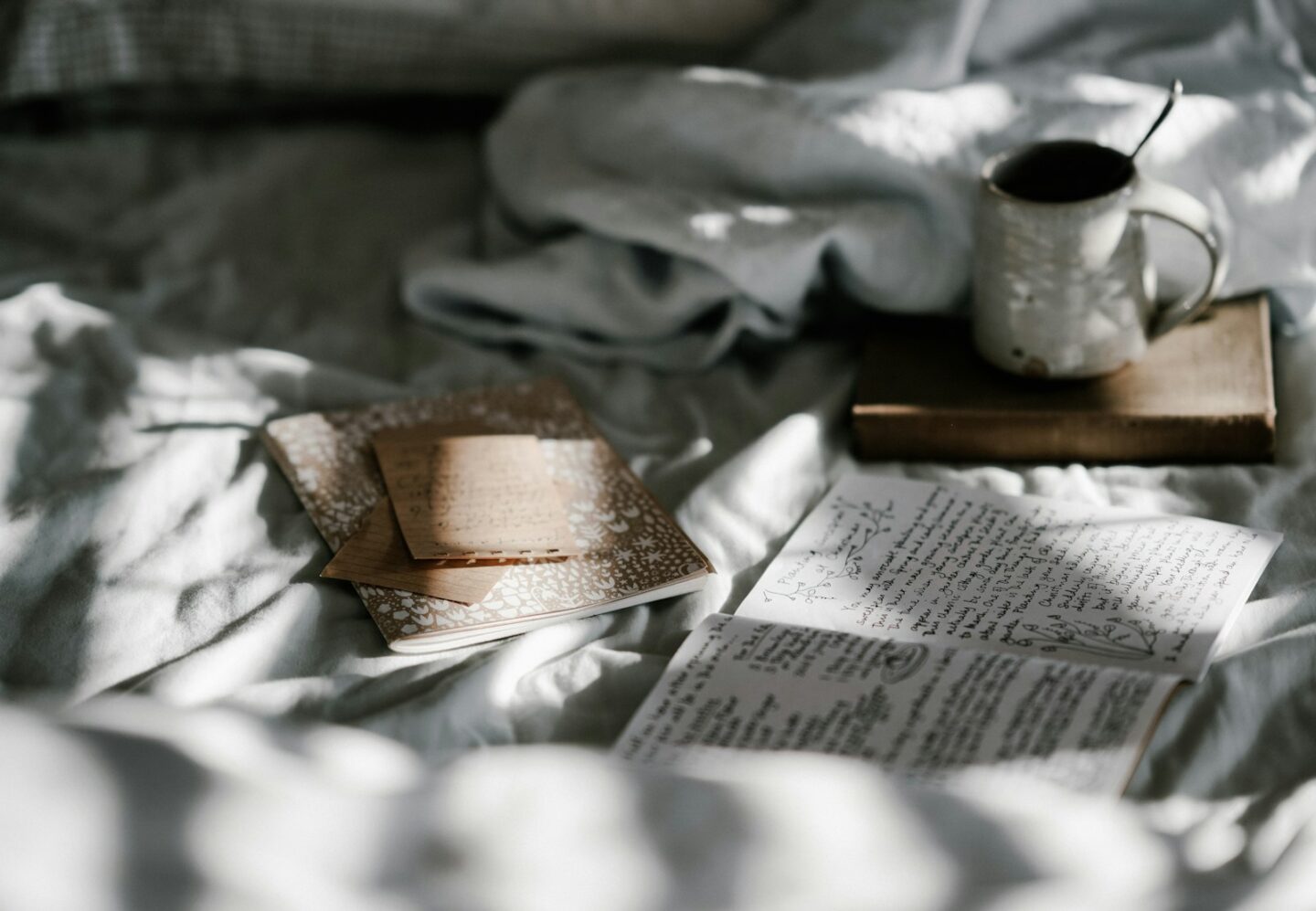 white mug on cosy bed setup with notebooks and book