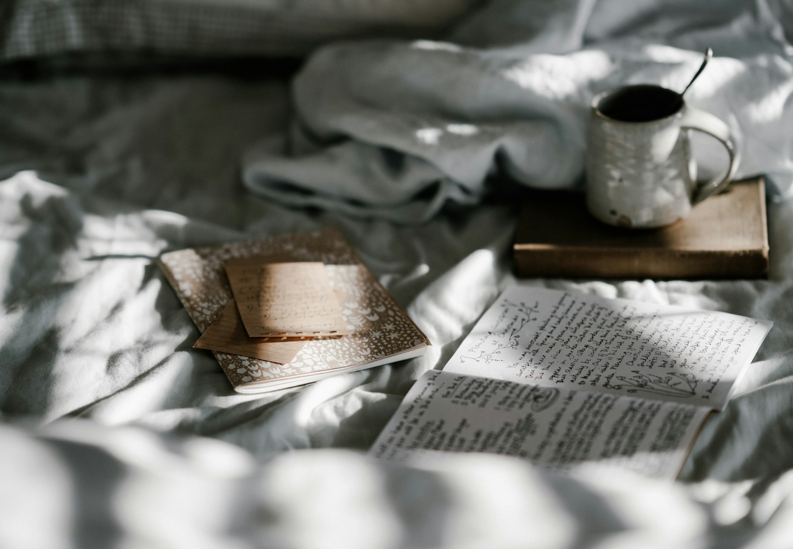 white mug on cosy bed setup with notebooks and book