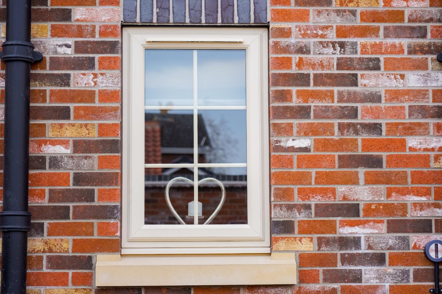 window in house with heart-shaped candle inside