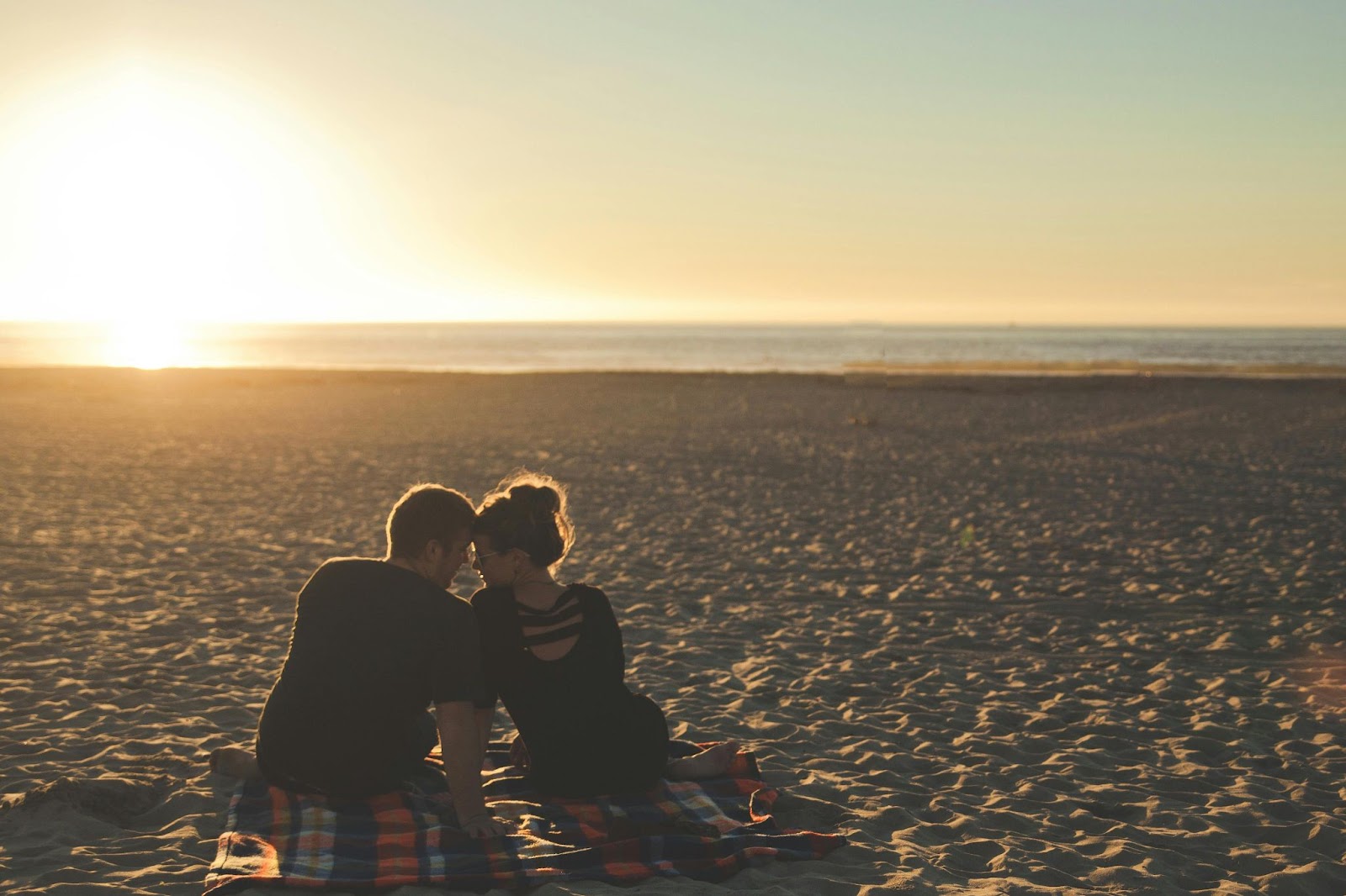 man and woman with heads together on beach