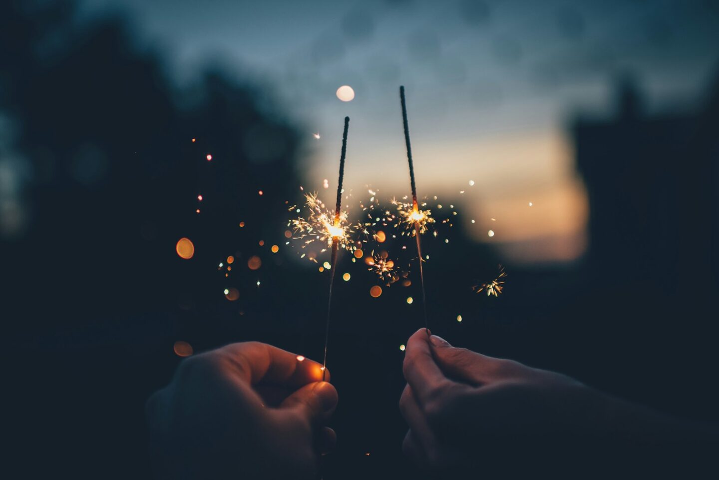 two people holding sparklers shallow focus photography