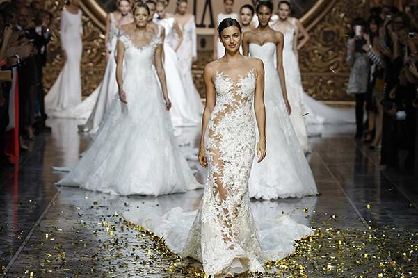 women wearing white bridal gowns walking down runway