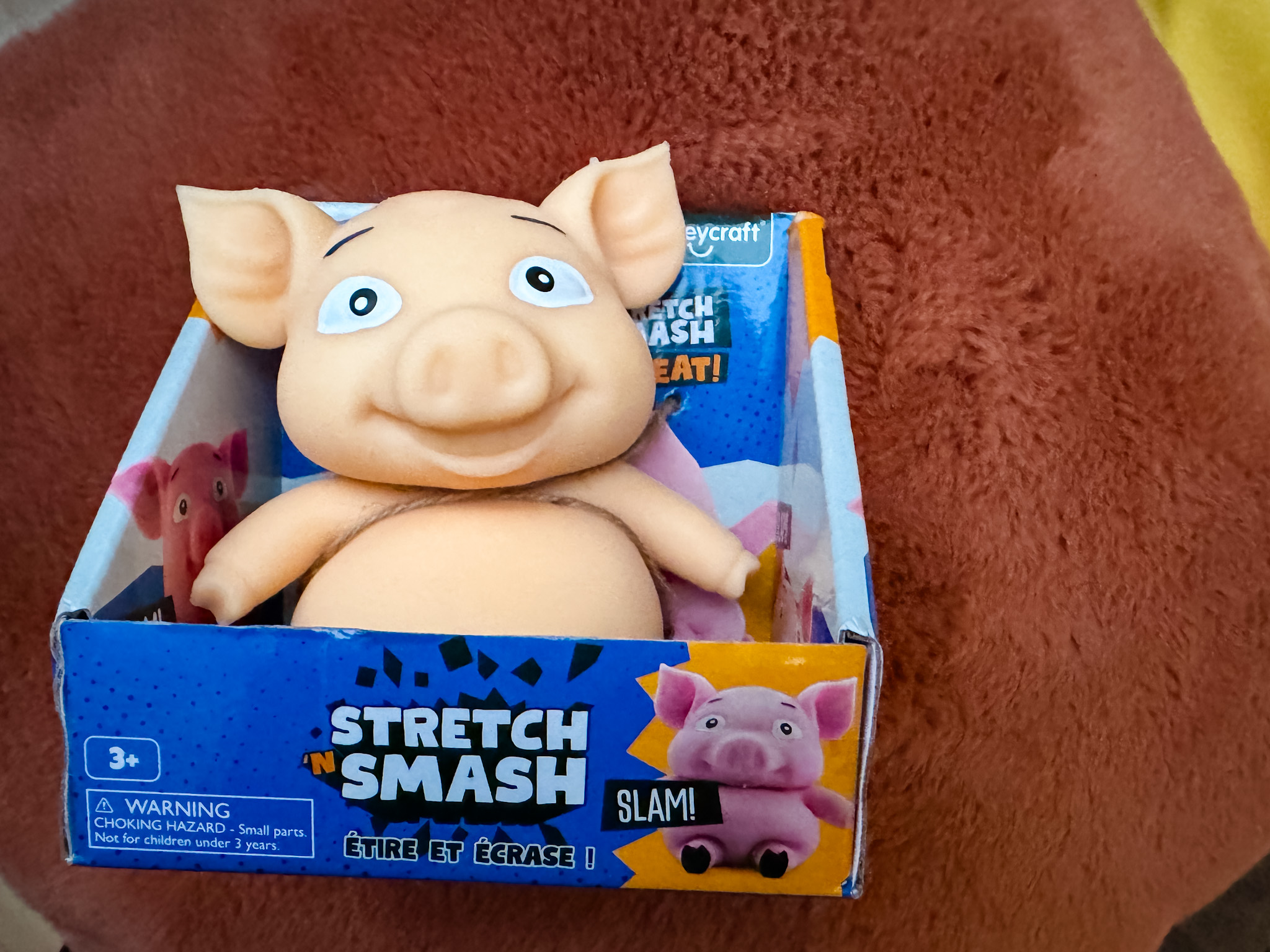 stretch and smash pig toy fidget in box on orange fluffy cushion