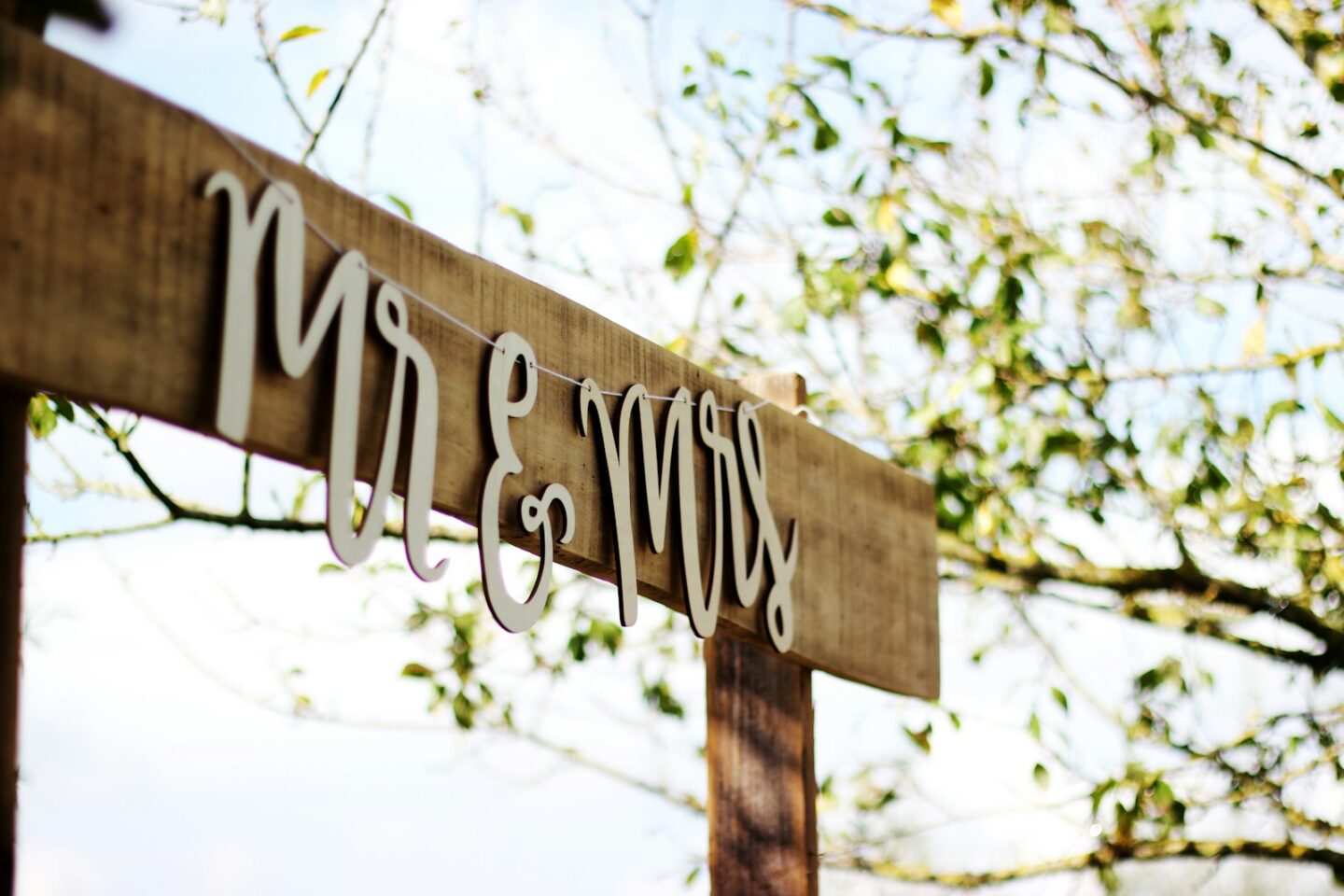 Mr and Mrs signage on wooden plinth with tree leaves behind