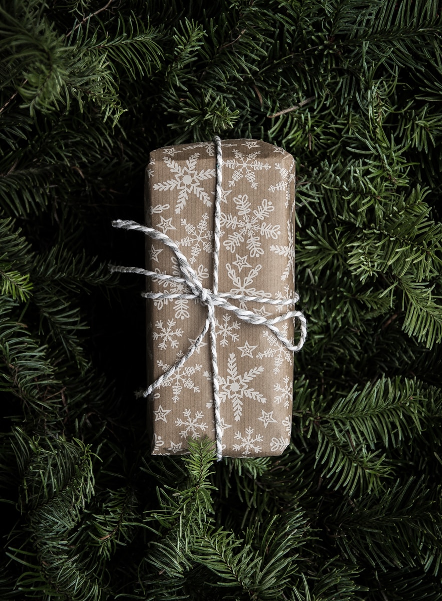 brown and white paper wrapped gift on green christmas tree