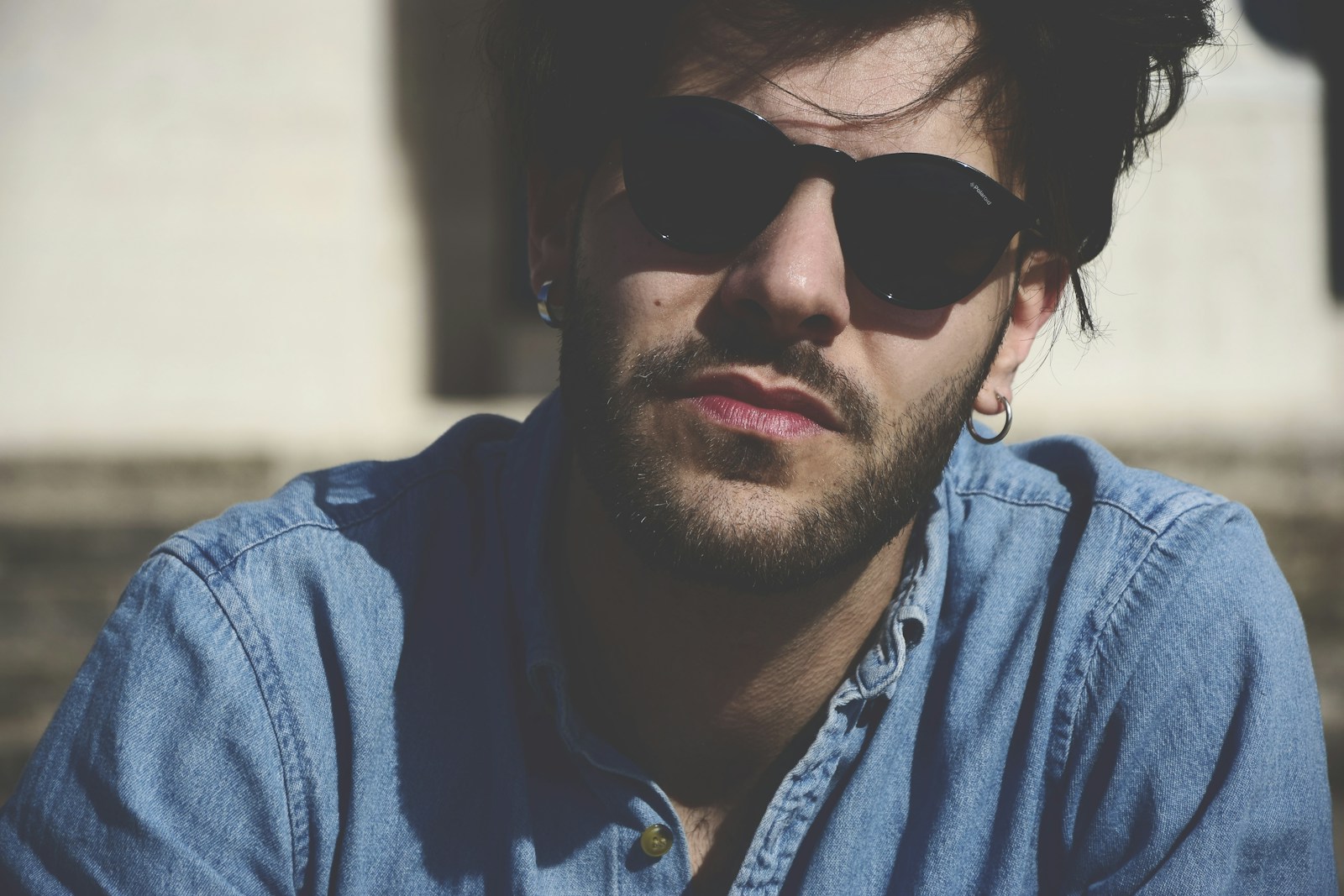 man wearing blue denim shirt and black sunglasses