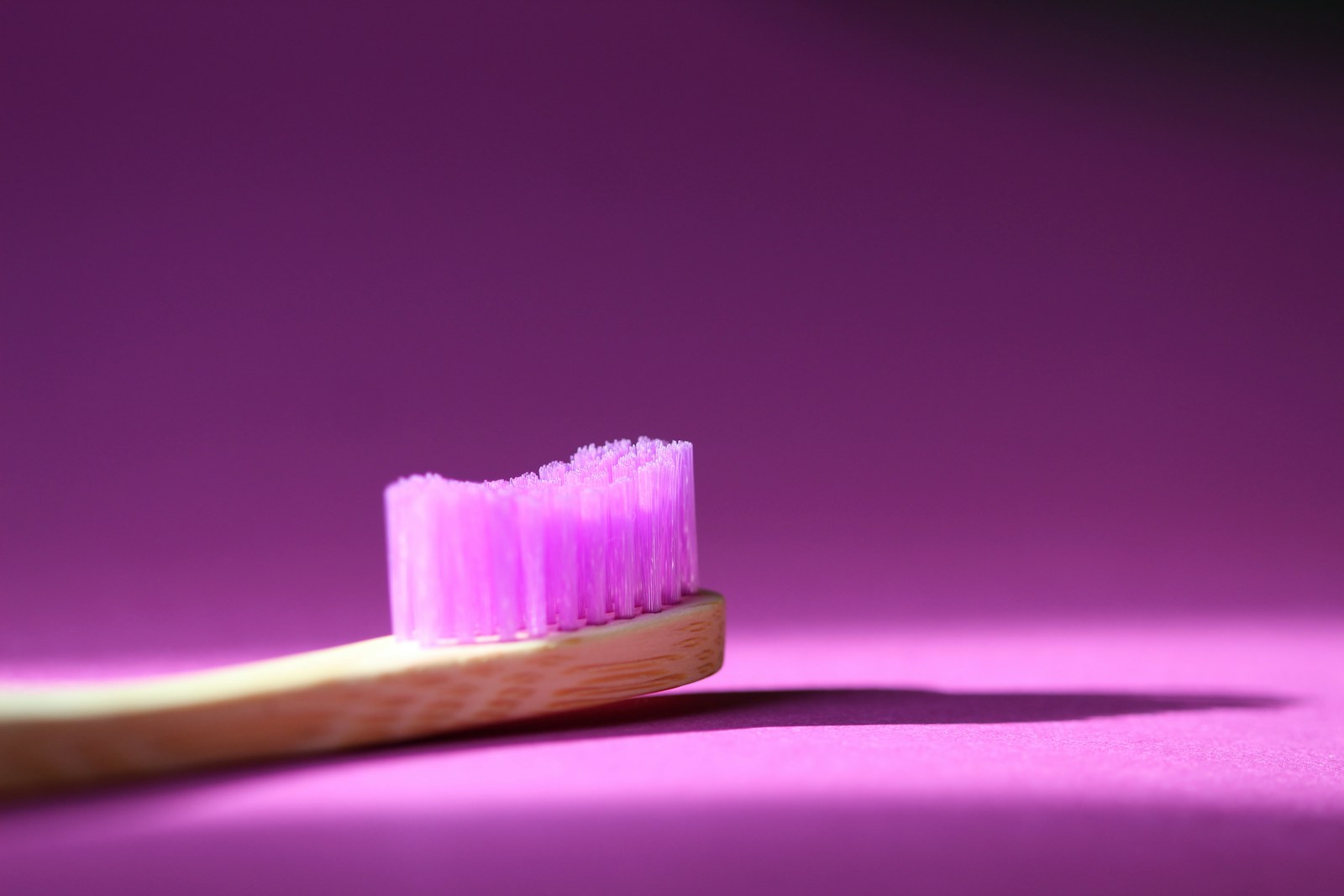 wooden toothbrush with pink bristles on pink background