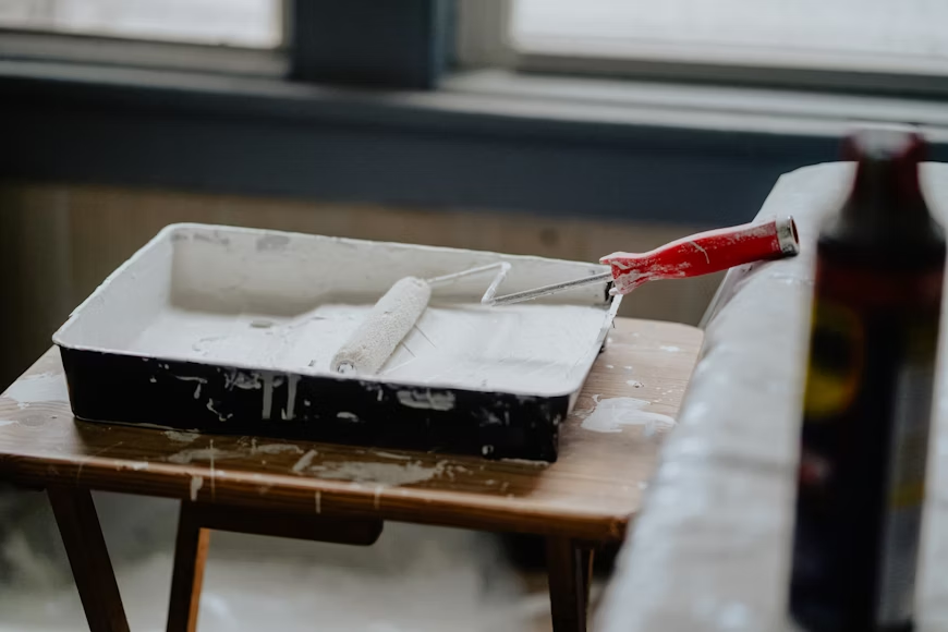 paint tray with white paint in it and roller on brown table