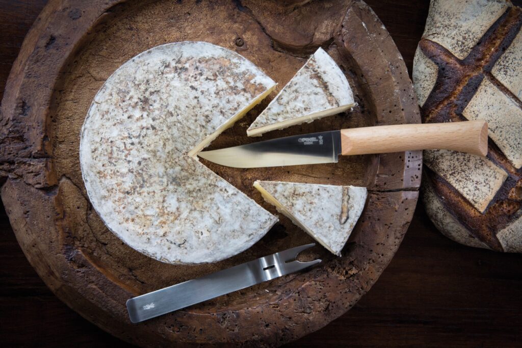 Opinel Cheese knife set cutting into cheese on a cheese board