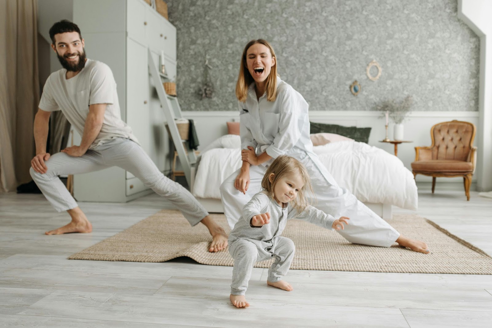 man, woman and child strecthing in white bedroom in light clothing