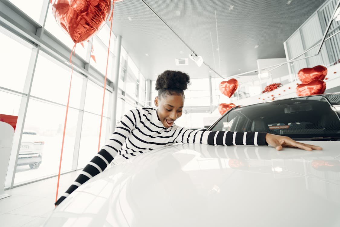 teenager with big smile holding onto new car in showroom