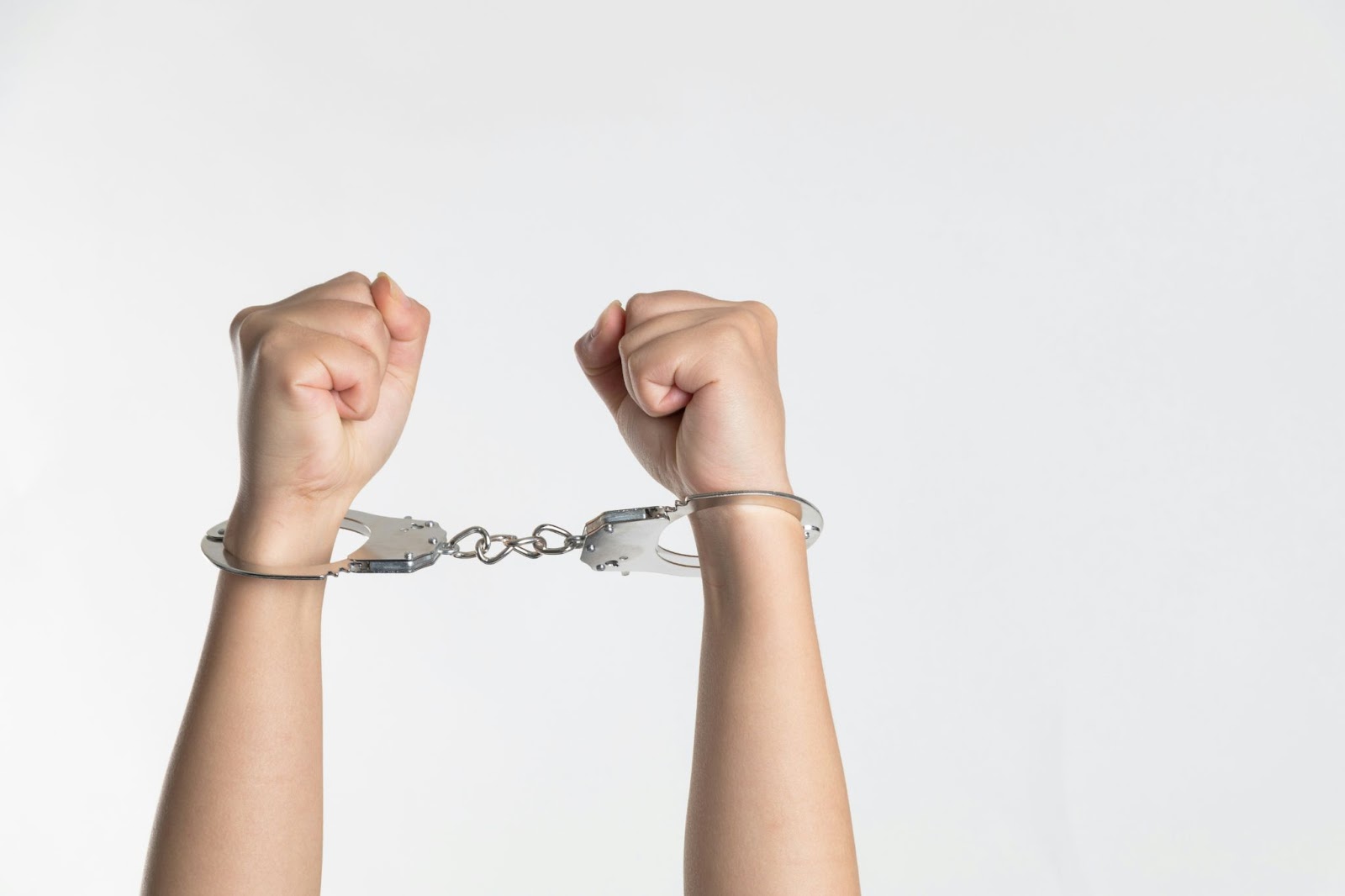 person's arms in the air with handcuffs on