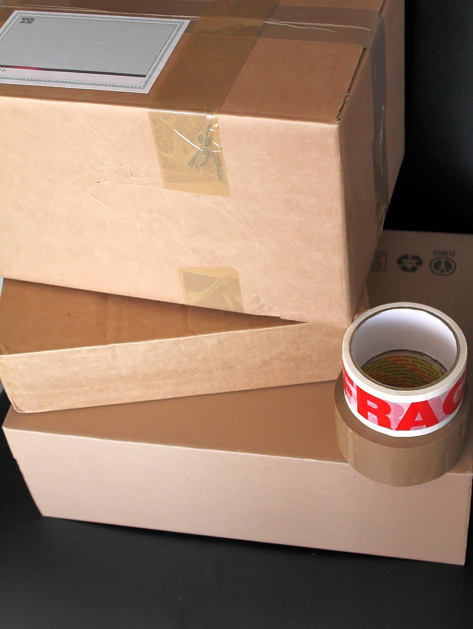 brown cardboard boxes piled up with brown paper tape and red and white 'fragile' on one of them