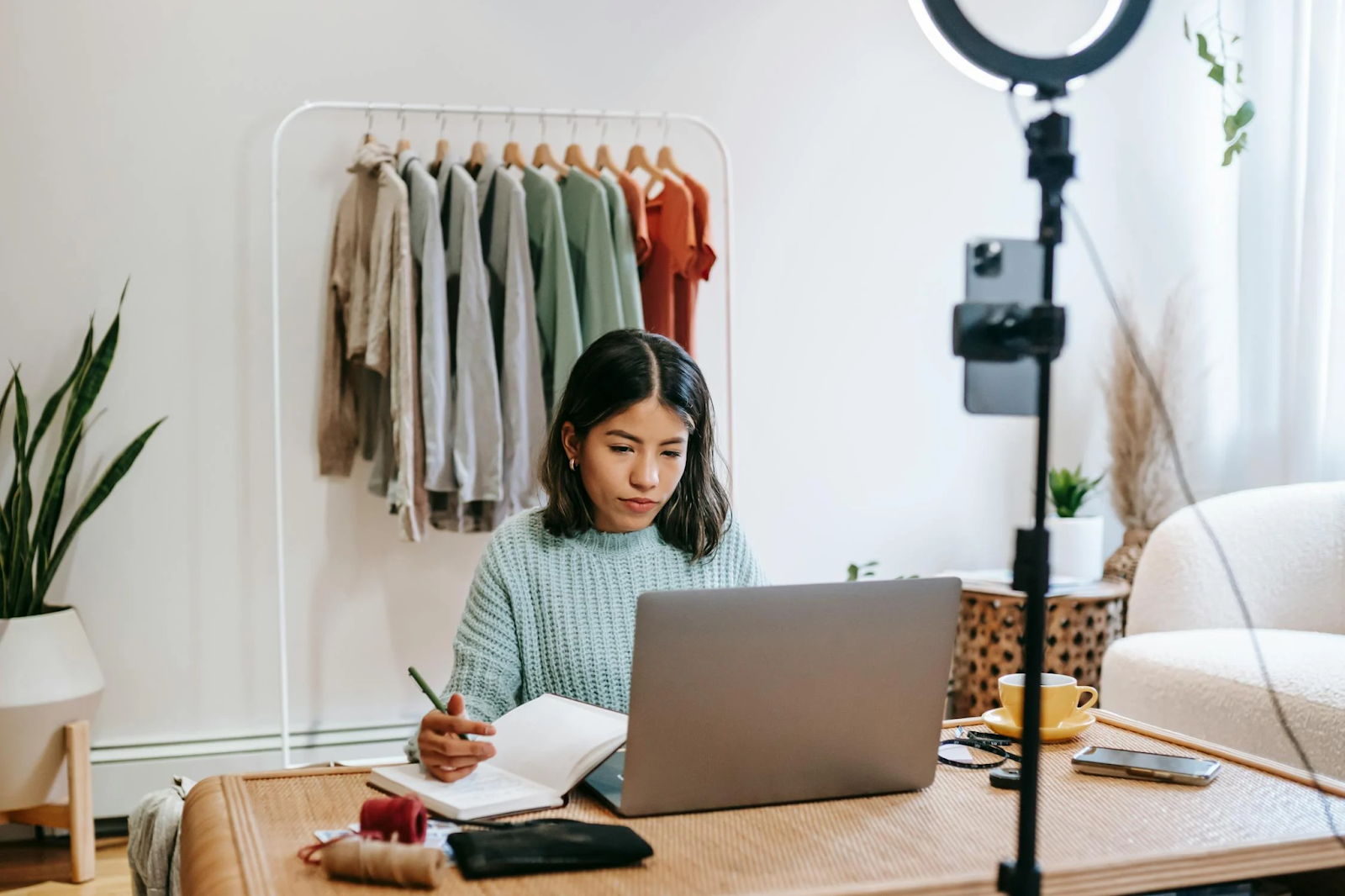 woman on laptop and writing with pen in notebook