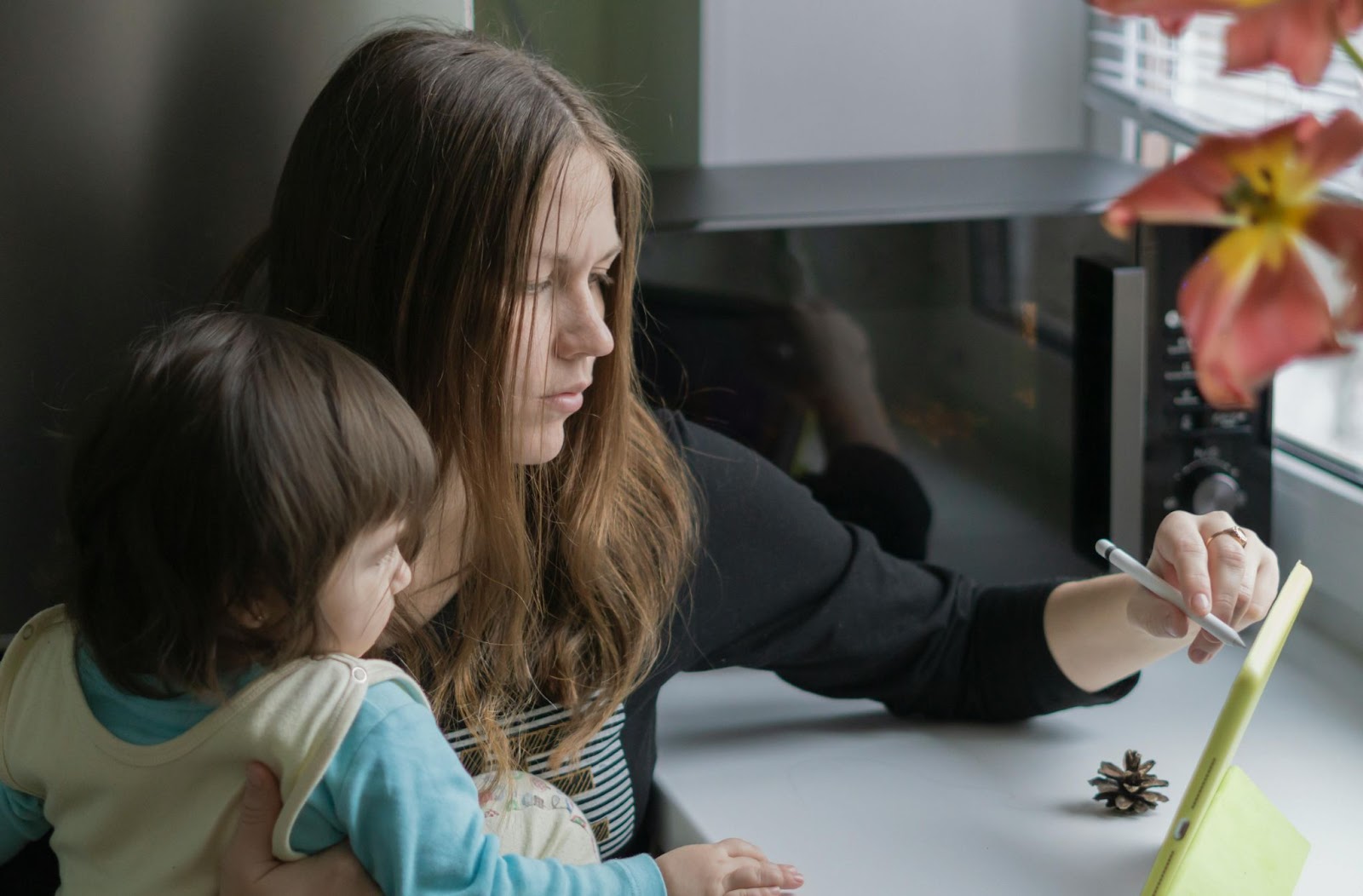 mother and child sitting at table with mum holding up a tablet